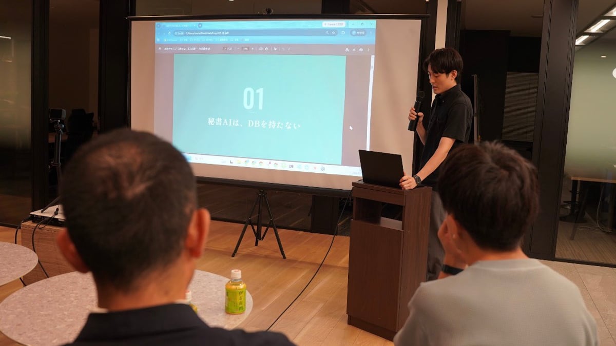 当社オフィスで開催されたAIナイトで、スクリーンの横に立ち参加者に向けて話す当社代表